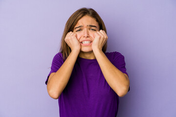 Young skinny caucasian girl teenager on purple background crying, unhappy with something, agony and confusion concept.