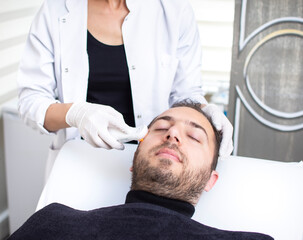 Obraz na płótnie Canvas Handsome man is undergoing anti-aging ultrasound procedure at wellness center. Guy in beauty salon. Modern Cosmetology for men. Professional Cosmetologist. Men's Beauty Concept.