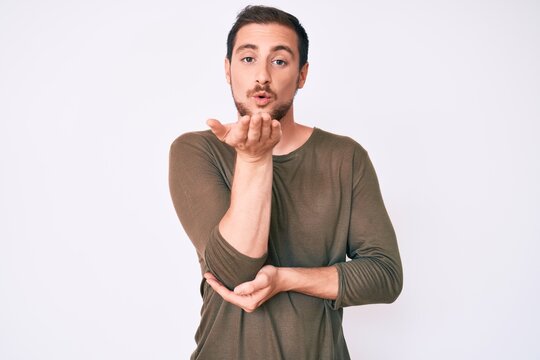 Young handsome man wearing casual clothes looking at the camera blowing a kiss with hand on air being lovely and sexy. love expression.