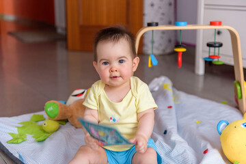Bebe pequeño con juguetes en casa con vestido amarillo