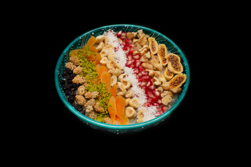 Closeup of traditional Turkish Dessert Asure or Ashura (aka Noah Pudding) in traditional green bowl isolated on black background.