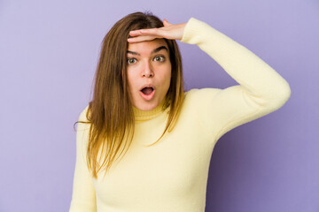 Fototapeta premium Young skinny caucasian girl teenager on purple background looking far away keeping hand on forehead.