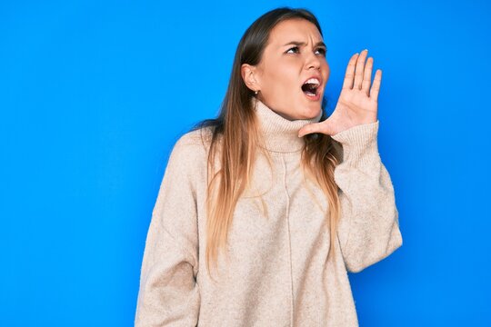 Beautiful caucasian woman wearing wool winter sweater shouting and screaming loud to side with hand on mouth. communication concept.