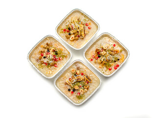 Closeup of traditional Turkish Dessert Asure or Ashura (aka Noah Pudding) in disposable aluminum bowls isolated on white background. with copy space for text. 