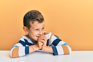 Adorable caucasian kid wearing casual clothes sitting on the table laughing nervous and excited...