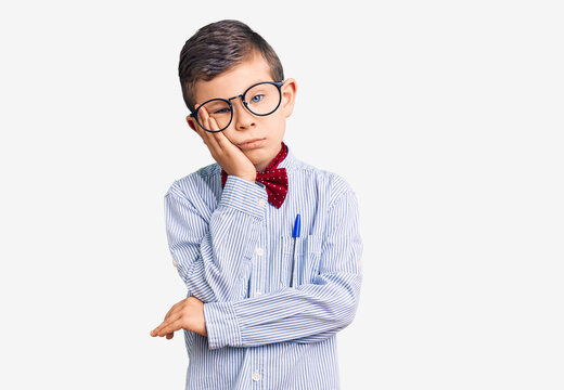 Cute blond kid wearing nerd bow tie and glasses thinking looking tired and bored with depression problems with crossed arms.