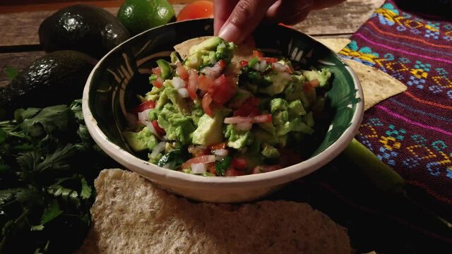Mexican guacamole with tomato and jalapeno pepper on wooden background