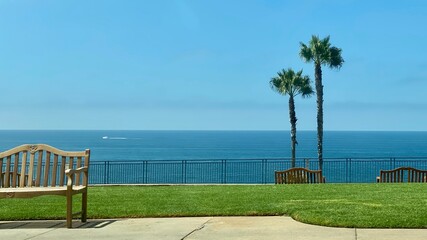 Pacific Ocean with palm trees, chairs and railings on a slope overlooking the sea at Laguna Beach in California, USA