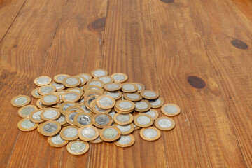 A pile with a lot of Real brazilian money coins on a wood table