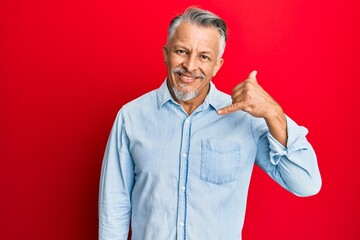 Middle age grey-haired man wearing casual clothes smiling doing phone gesture with hand and fingers like talking on the telephone. communicating concepts.