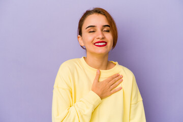 Young arab mixed race woman laughs out loudly keeping hand on chest.