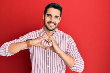 Young hispanic man wearing business shirt smiling in love showing heart symbol and shape with hands. romantic concept.