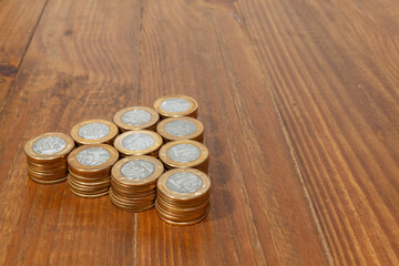 A pile with a lot of Real brazilian money coins stacked on a wood table