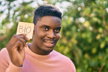 Fototapeta premium Young african american man smiling happy holding bio message reminder at the park.