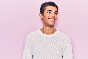 Young african amercian man wearing casual clothes looking to side, relax profile pose with natural face and confident smile.