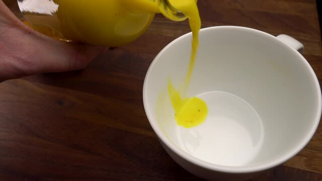 Pouring Golden Milk Turmeric Drink into Cup. Healthy Anti-Inflammatory Detox. 