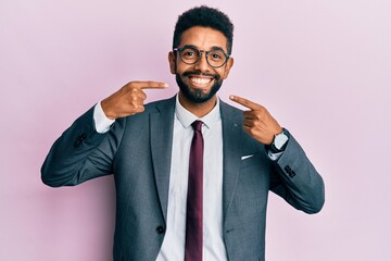 Handsome hispanic business man with beard wearing business suit and tie smiling cheerful showing and pointing with fingers teeth and mouth. dental health concept.