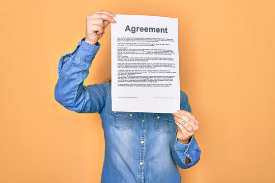 Woman holding agreement document paper standing over isolated yellow background