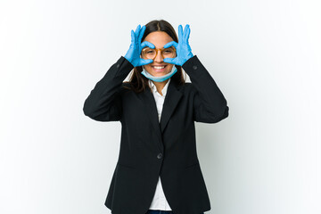 Young business latin woman wearing a mask to protect from covid isolated on white background showing okay sign over eyes