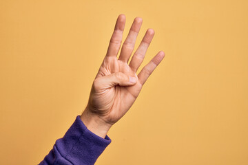 Hand of caucasian young man showing fingers over isolated yellow background counting number 4 showing four fingers