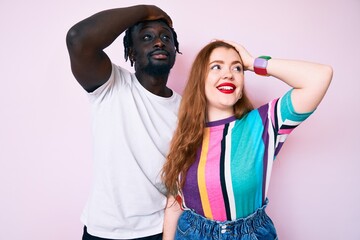 Interracial couple wearing casual clothes smiling confident touching hair with hand up gesture, posing attractive and fashionable