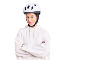 Beautiful brunette young woman wearing bike helmet and sporty clothes happy face smiling with crossed arms looking at the camera. positive person.