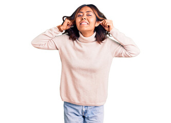 Young beautiful mixed race woman wearing winter turtleneck sweater smiling pulling ears with fingers, funny gesture. audition problem