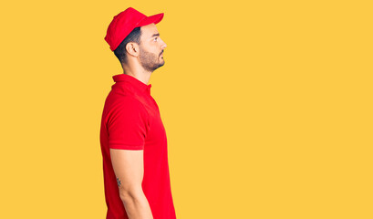 Young handsome hispanic man wearing delivery courier uniform looking to side, relax profile pose with natural face with confident smile.