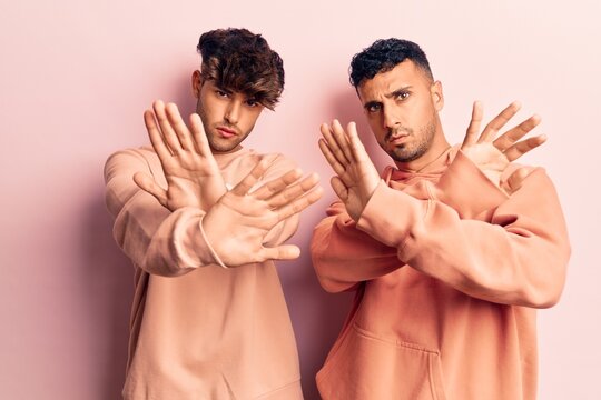 Young gay couple wearing casual clothes rejection expression crossing arms and palms doing negative sign, angry face