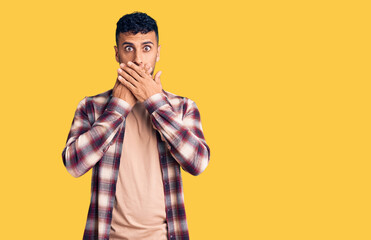 Young hispanic man wearing casual clothes shocked covering mouth with hands for mistake. secret concept.