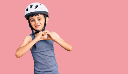 Little cute boy kid wearing bike helmet smiling in love showing heart symbol and shape with hands. romantic concept.