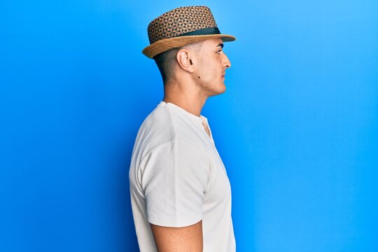 Hispanic young man wearing summer hat looking to side, relax profile pose with natural face with confident smile.