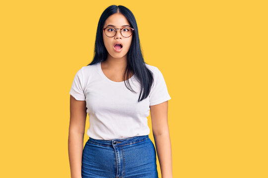 Young beautiful asian girl wearing casual clothes and glasses afraid and shocked with surprise and amazed expression, fear and excited face.