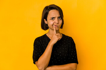 Young hispanic woman isolated on yellow unhappy looking in camera with sarcastic expression.