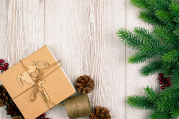Fir branches and cones. Christmas background with decorations, reindeer and gift boxe on wooden board. Top view.