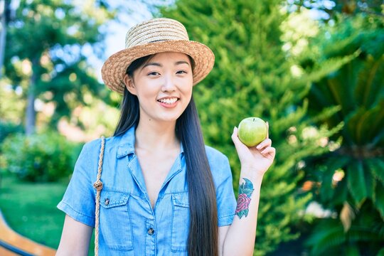 Young chinese tourist woman eating green apple at the park.