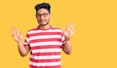 Naklejka premium Handsome latin american young man wearing casual clothes and glasses showing and pointing up with fingers number nine while smiling confident and happy.