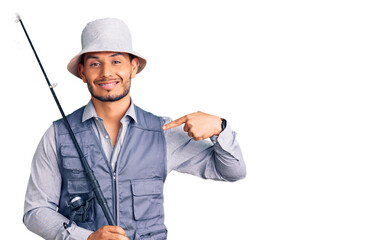 Handsome latin american young man wearing fisherman equipment pointing finger to one self smiling...