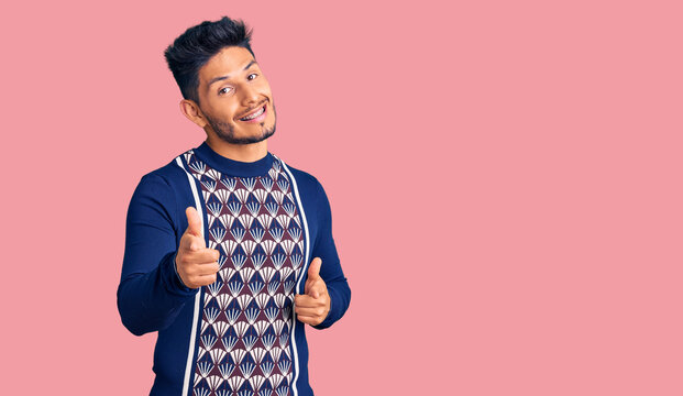 Handsome latin american young man wearing casual winter sweater pointing fingers to camera with happy and funny face. good energy and vibes.