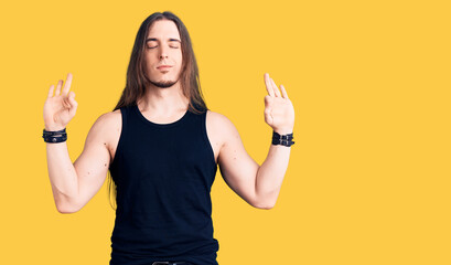 Young adult man with long hair wearing rocker style with black clothes and contact lenses relax and...