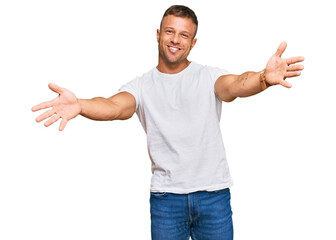 Naklejka premium Handsome muscle man wearing casual white tshirt looking at the camera smiling with open arms for hug. cheerful expression embracing happiness.