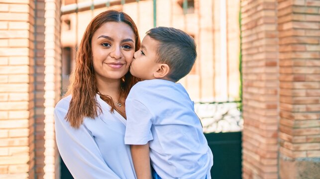 Adorable latin mother and son smiling happy hugging and kissing at the city.
