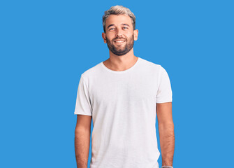 Fototapeta premium Young handsome blond man wearing casual t-shirt with a happy and cool smile on face. lucky person.