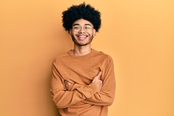 Obraz na płótnie Canvas Young african american man with afro hair wearing casual winter sweater happy face smiling with crossed arms looking at the camera. positive person.