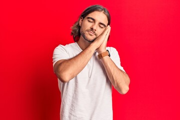 Young handsome man wearing casual clothes sleeping tired dreaming and posing with hands together while smiling with closed eyes.