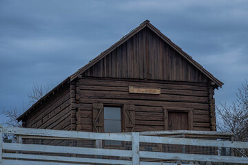 2020-12-07 A OLD WOODEN CABIN WITH A WHITE FENCE AND CLOUDY SKY