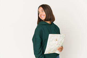 Obraz premium Young hispanic traveler woman holding a map looks aside smiling, cheerful and pleasant.