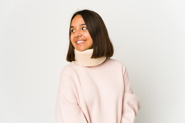 Young hispanic woman wearing a collar looks aside smiling, cheerful and pleasant.