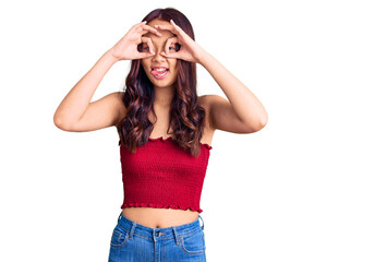 Fototapeta premium Young beautiful chinese girl wearing casual clothes doing ok gesture like binoculars sticking tongue out, eyes looking through fingers. crazy expression.