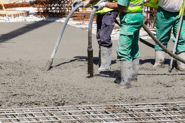 workers stirring cement with hoses